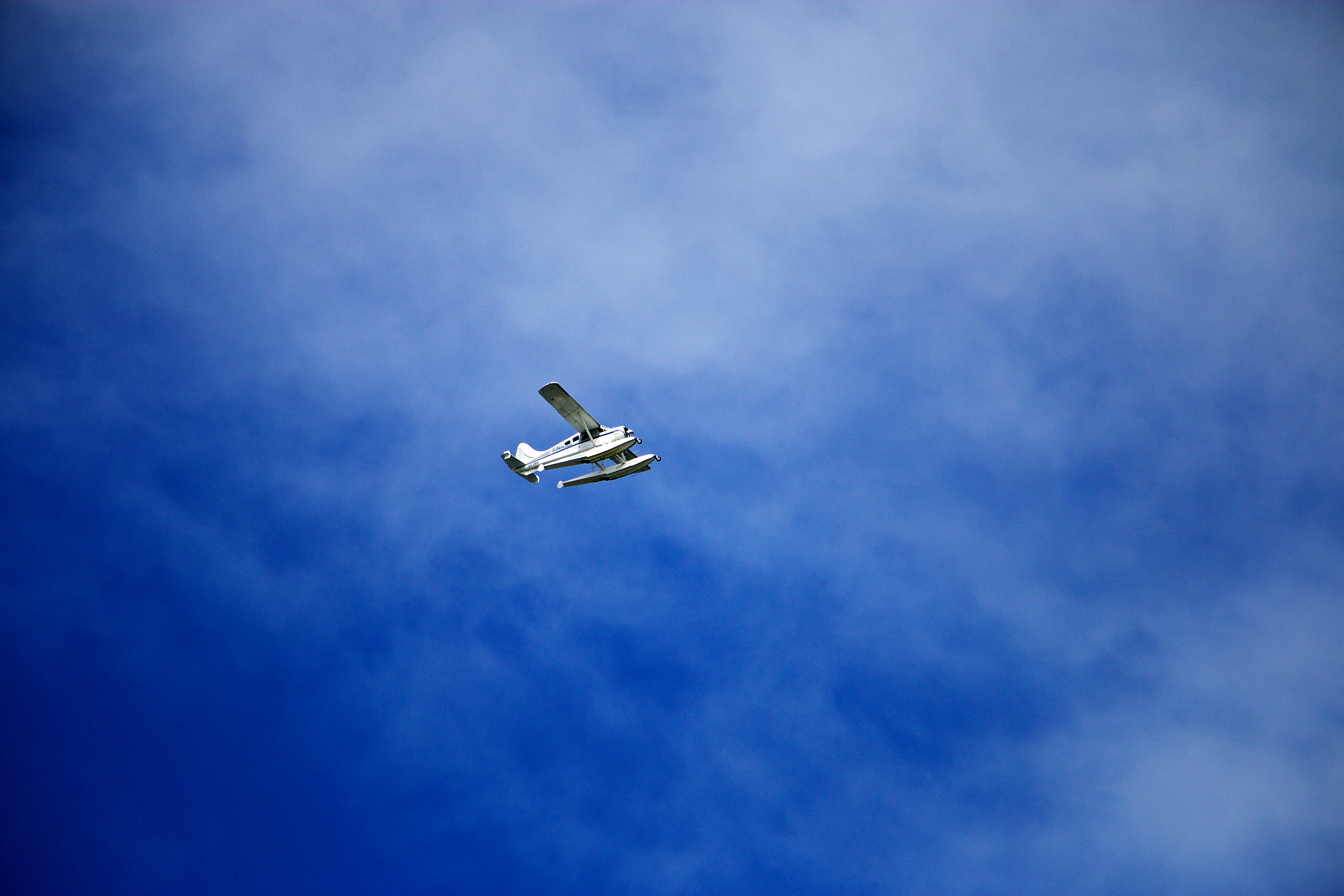 white flying biplane during white and blue sky